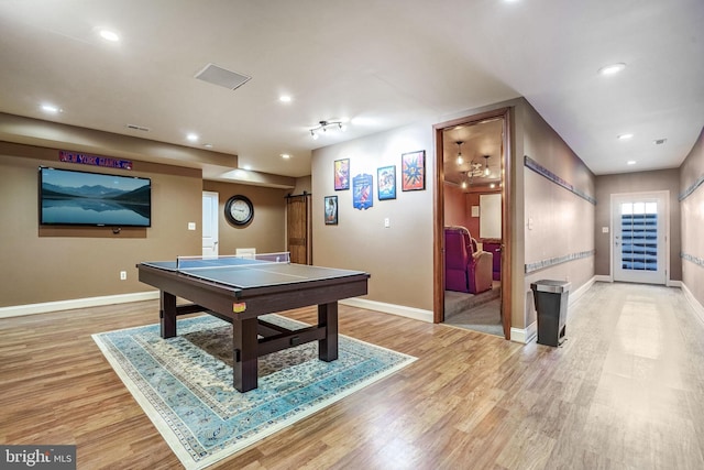 playroom with a barn door and light hardwood / wood-style flooring