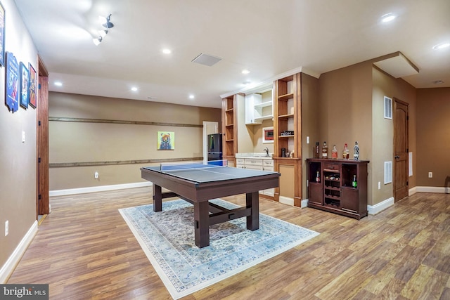 playroom with wet bar and light hardwood / wood-style flooring