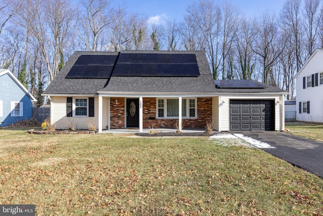 view of front of home with a garage, solar panels, a porch, and a front yard