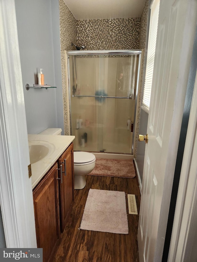 bathroom with wood-type flooring, toilet, an enclosed shower, and vanity