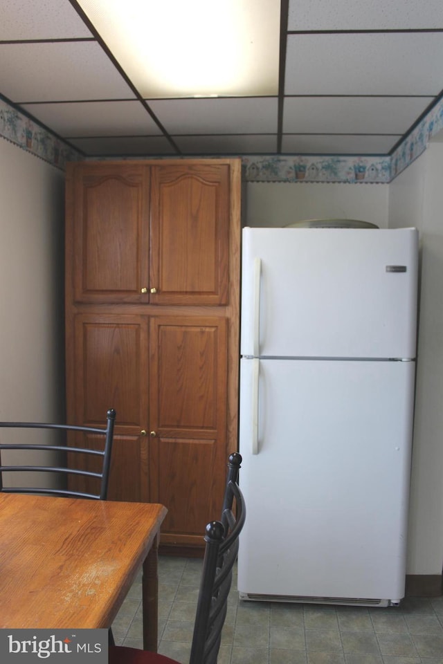 kitchen featuring white fridge, wood counters, tile patterned flooring, and a drop ceiling