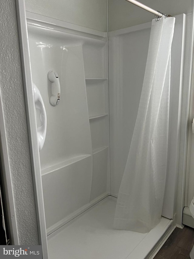 bathroom with wood-type flooring and walk in shower