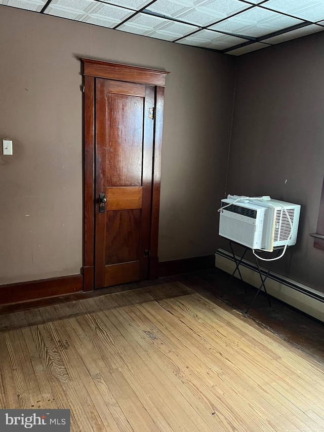 spare room featuring a baseboard heating unit, light hardwood / wood-style floors, and an AC wall unit