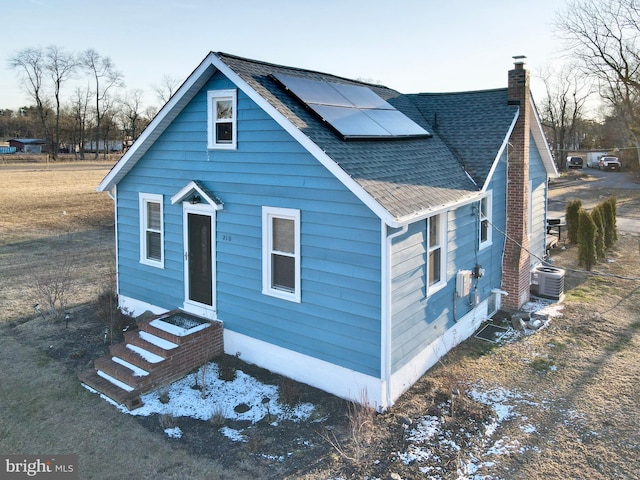 view of front of home featuring cooling unit and solar panels