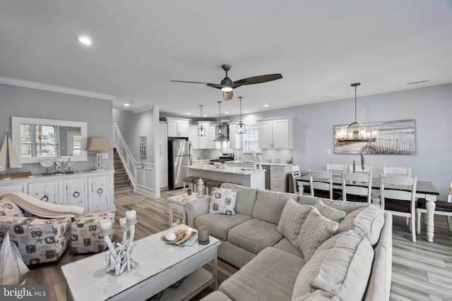 living room with ceiling fan with notable chandelier, plenty of natural light, and light wood-type flooring