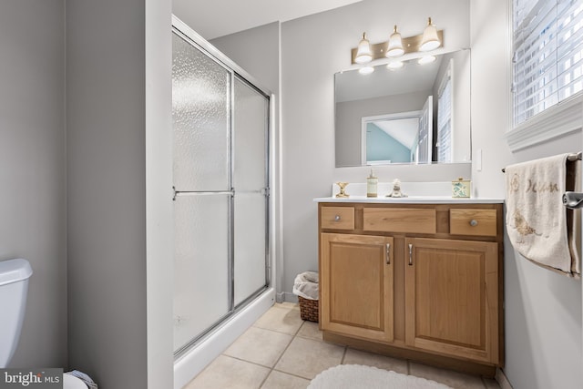 bathroom featuring toilet, vanity, tile patterned flooring, and a shower with door