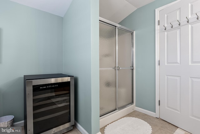 bathroom with lofted ceiling, a shower with door, tile patterned floors, and beverage cooler