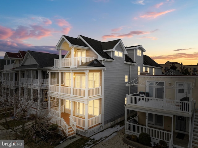 back house at dusk featuring a balcony