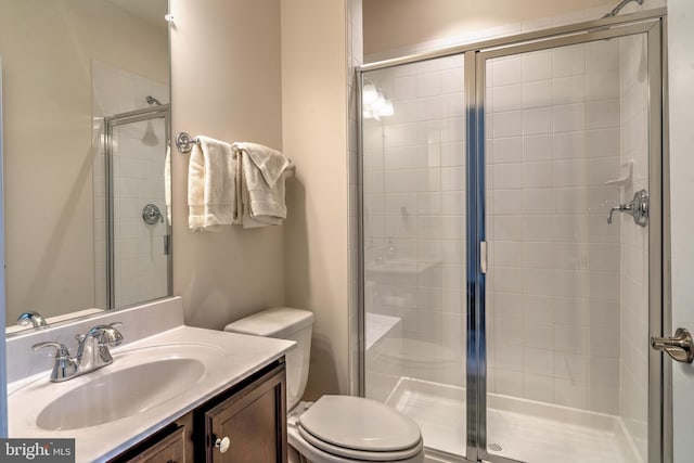 bathroom featuring a shower with shower door, toilet, and vanity