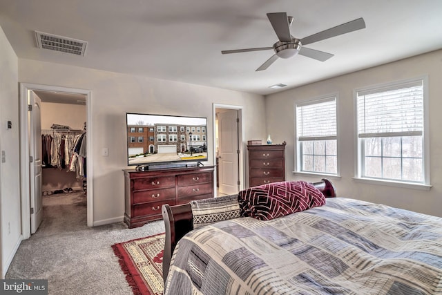 bedroom featuring ceiling fan, light carpet, a closet, and a walk in closet