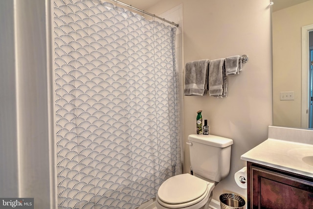 bathroom with toilet, vanity, and curtained shower