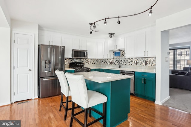 kitchen with light hardwood / wood-style floors, a center island, a breakfast bar area, stainless steel appliances, and white cabinets