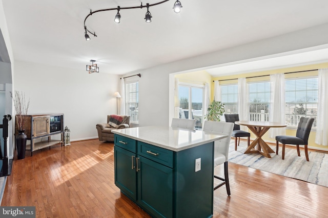 kitchen featuring hanging light fixtures, a kitchen breakfast bar, light hardwood / wood-style floors, and a center island