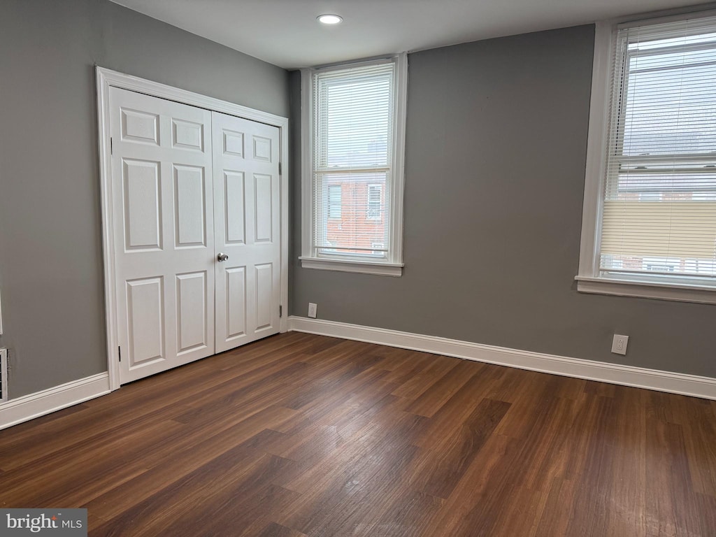 unfurnished bedroom featuring dark wood-type flooring, a closet, recessed lighting, and baseboards