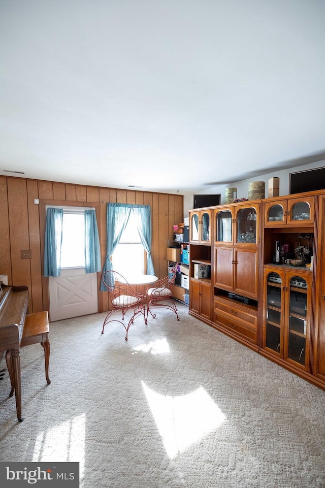 sitting room with light colored carpet and wooden walls