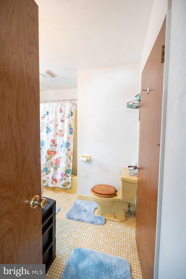 bathroom with shower / tub combo, tile patterned floors, and toilet