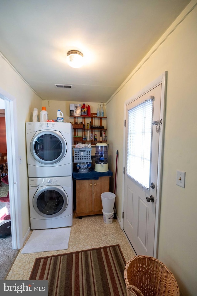 clothes washing area featuring cabinets and stacked washer / drying machine