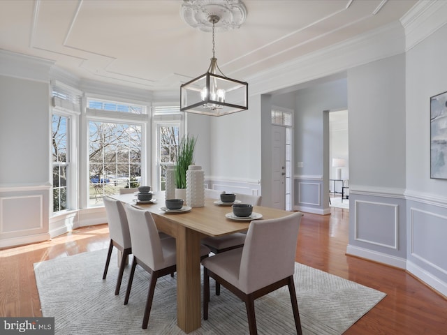 dining area featuring an inviting chandelier, ornamental molding, and wood-type flooring