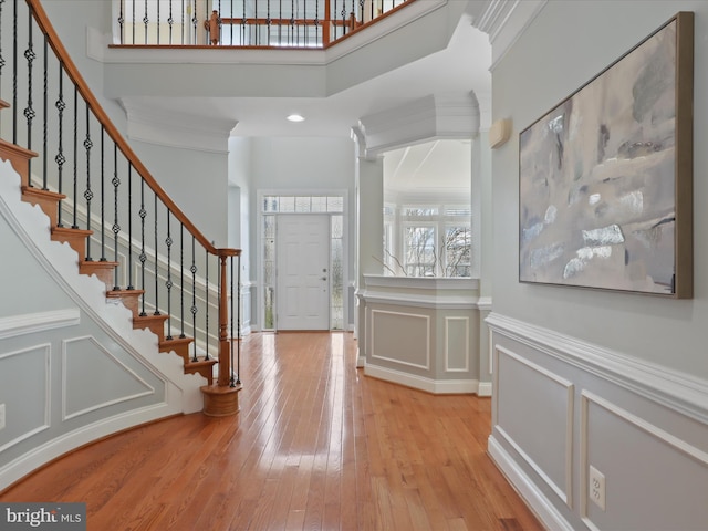 entrance foyer with a towering ceiling, light hardwood / wood-style flooring, and ornamental molding