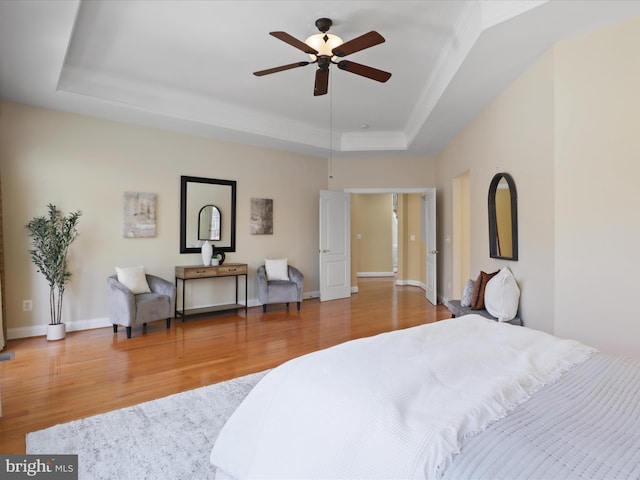 bedroom with a raised ceiling, wood-type flooring, and ornamental molding