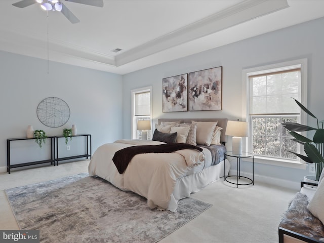 carpeted bedroom featuring ceiling fan and a raised ceiling