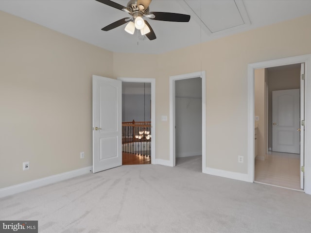 unfurnished bedroom with a walk in closet, light colored carpet, a closet, and ceiling fan