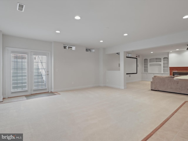 unfurnished living room featuring built in features and light colored carpet