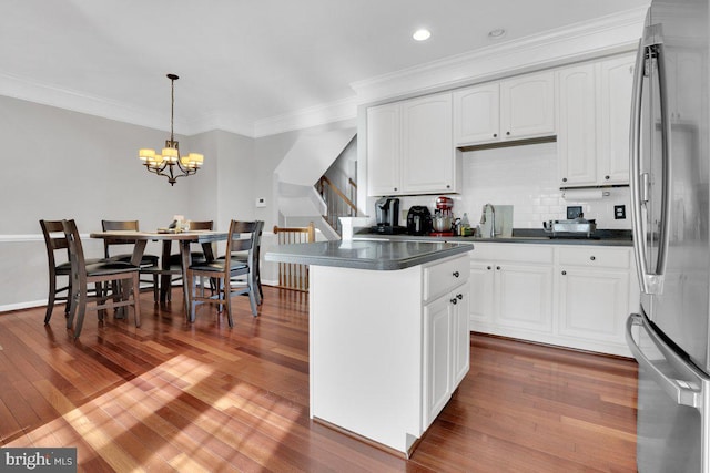 kitchen featuring pendant lighting, stainless steel fridge, tasteful backsplash, and white cabinets