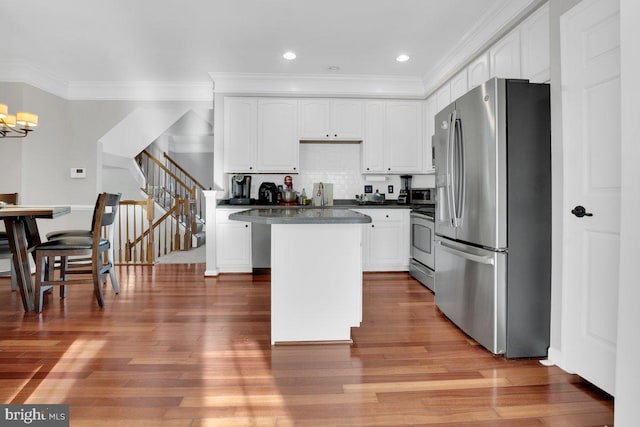 kitchen featuring a kitchen island, appliances with stainless steel finishes, white cabinetry, decorative backsplash, and an inviting chandelier