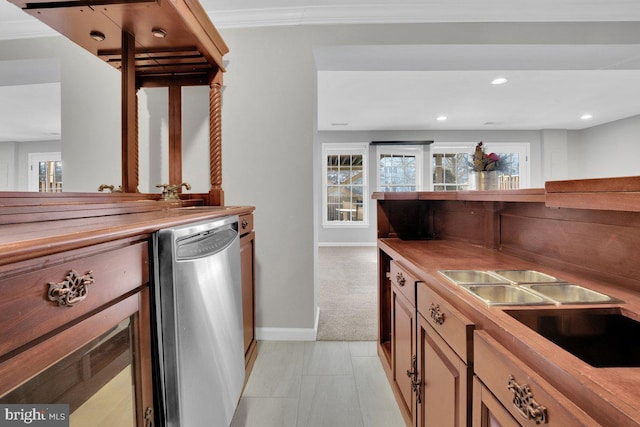 kitchen featuring sink, butcher block countertops, crown molding, stainless steel dishwasher, and light colored carpet