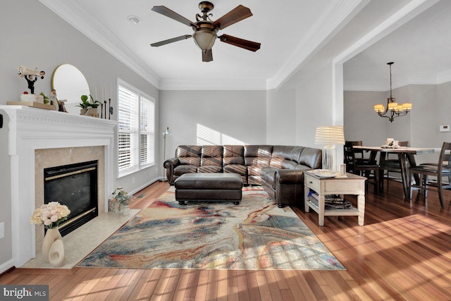 living room featuring ceiling fan with notable chandelier, ornamental molding, a high end fireplace, and wood-type flooring