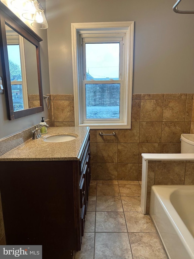 bathroom featuring vanity, a bathing tub, tile walls, and plenty of natural light