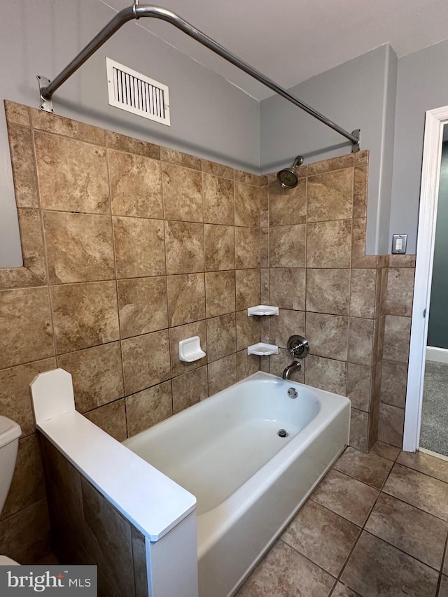 bathroom with tiled shower / bath combo, tile walls, tile patterned floors, and toilet