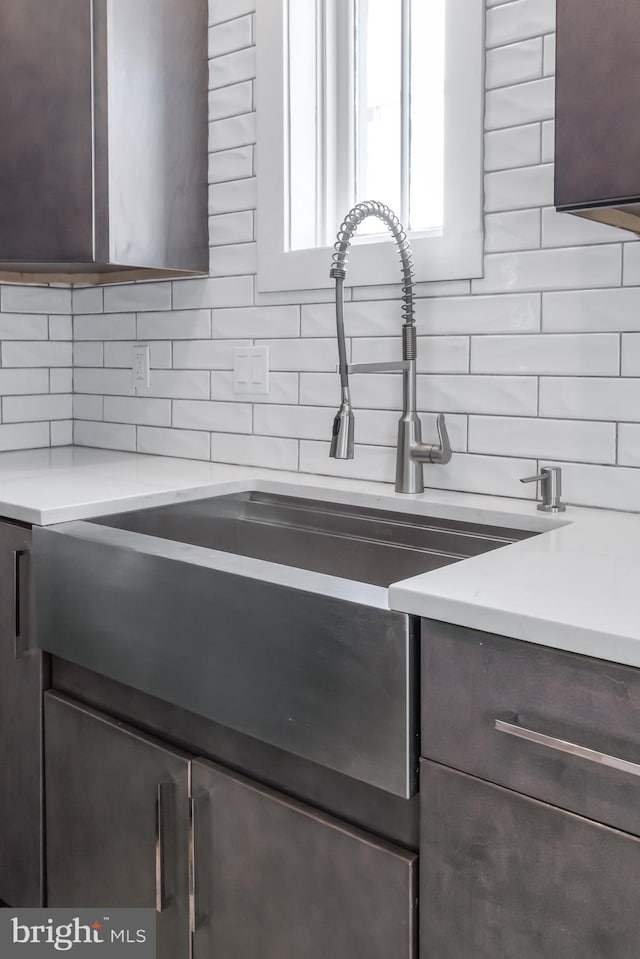 interior details featuring tasteful backsplash, dark brown cabinetry, and sink