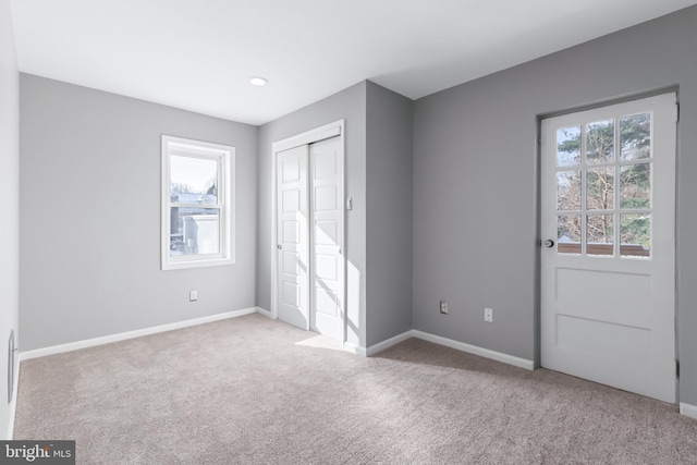 unfurnished bedroom with light colored carpet and a closet