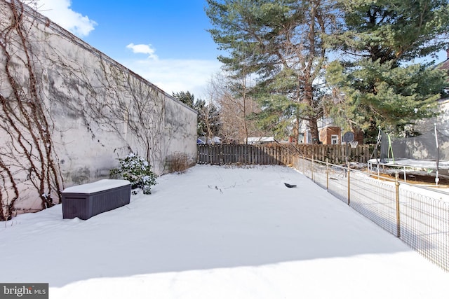 yard layered in snow with a trampoline