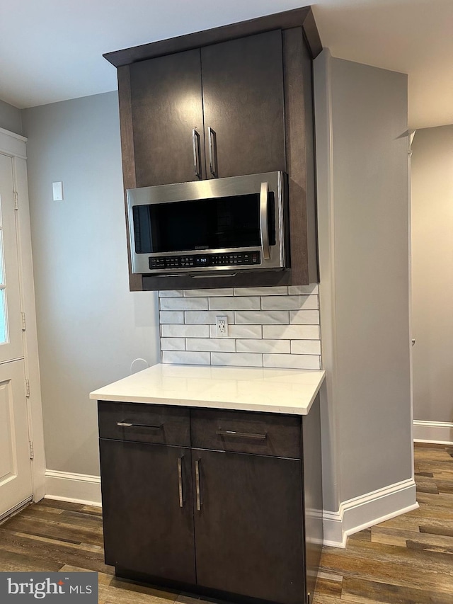 kitchen featuring dark hardwood / wood-style floors, backsplash, and dark brown cabinetry