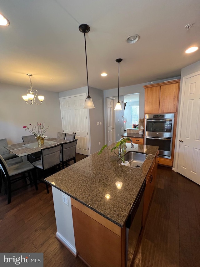 kitchen with appliances with stainless steel finishes, dark hardwood / wood-style flooring, a kitchen island with sink, and sink