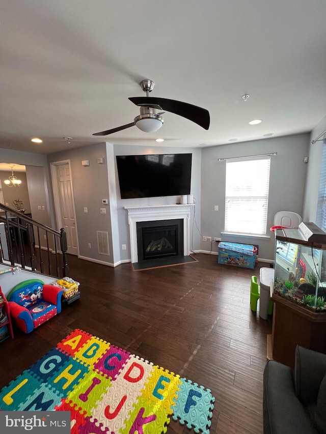 living room with dark wood-type flooring and ceiling fan with notable chandelier