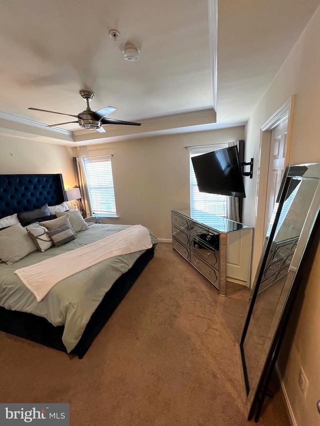 carpeted bedroom with ceiling fan and a raised ceiling