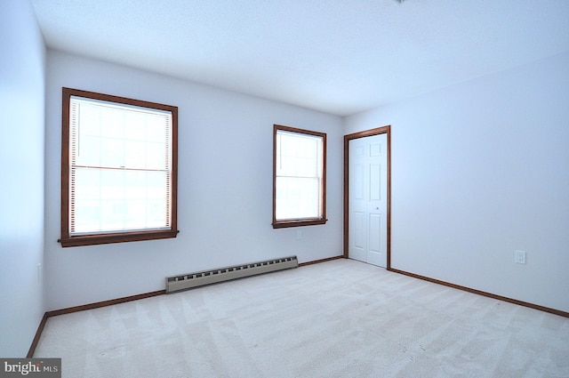 carpeted empty room with a baseboard heating unit