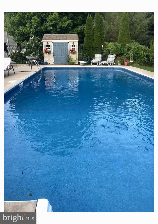 view of swimming pool with an outbuilding, a patio area, and a diving board