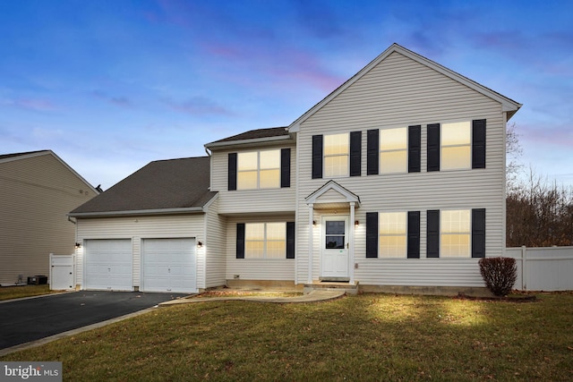 view of front of house with a garage, a lawn, and central air condition unit