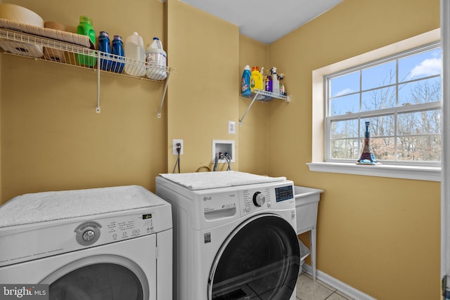 clothes washing area with light tile patterned floors and washing machine and dryer