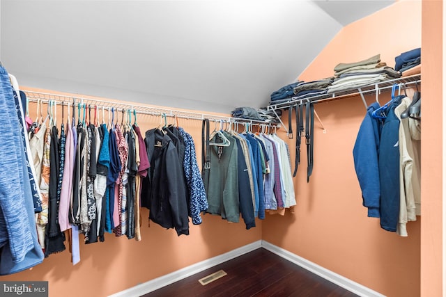 walk in closet with dark hardwood / wood-style floors and lofted ceiling