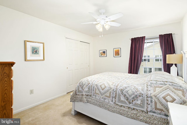 bedroom with ceiling fan, light carpet, and a closet