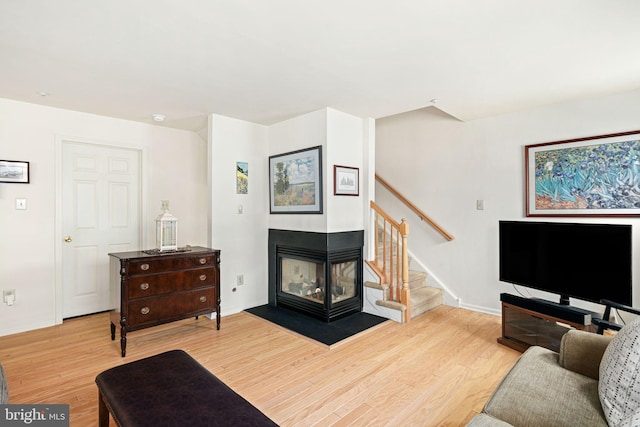 living room featuring wood-type flooring and a multi sided fireplace