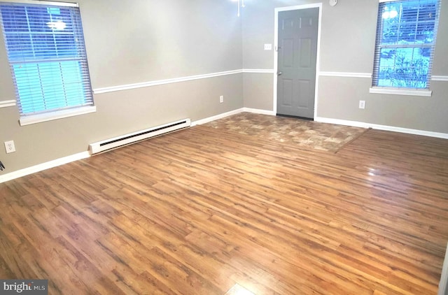 unfurnished room featuring wood-type flooring and a baseboard heating unit