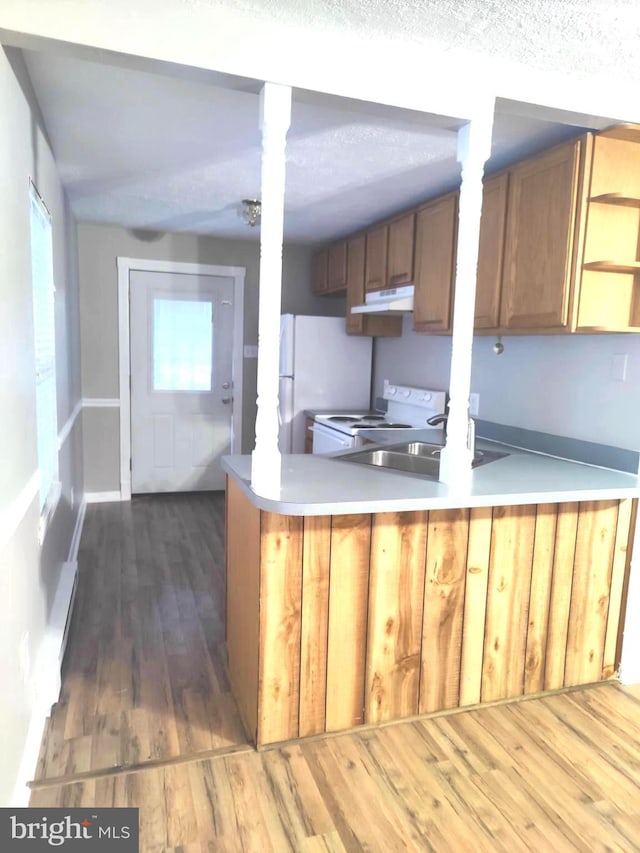 kitchen with sink, white appliances, dark hardwood / wood-style floors, a textured ceiling, and kitchen peninsula