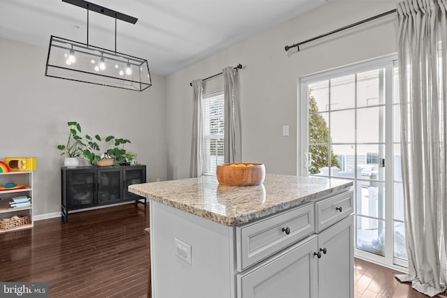 kitchen with light stone countertops, pendant lighting, a center island, white cabinetry, and dark hardwood / wood-style floors